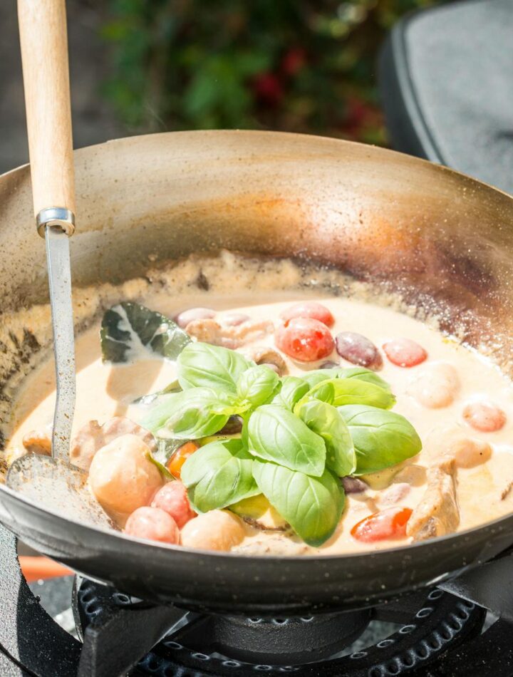 Delicious creamy tomato and basil sauce being prepared in a pan on an outdoor gas stove.