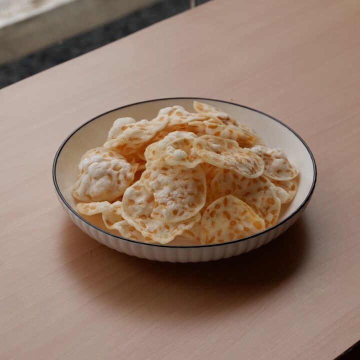 a bowl filled with cheetos sitting on top of a wooden table