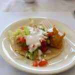 a white plate topped with a taco and a fork