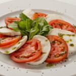 a white plate topped with sliced tomatoes and mozzarella