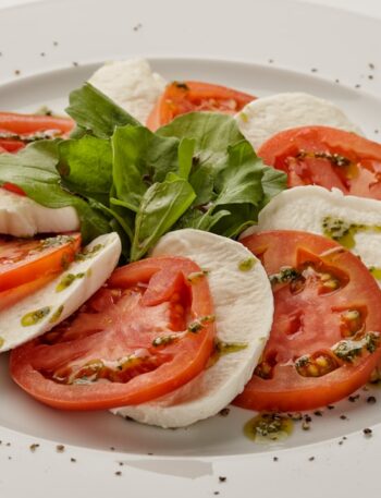 a white plate topped with sliced tomatoes and mozzarella