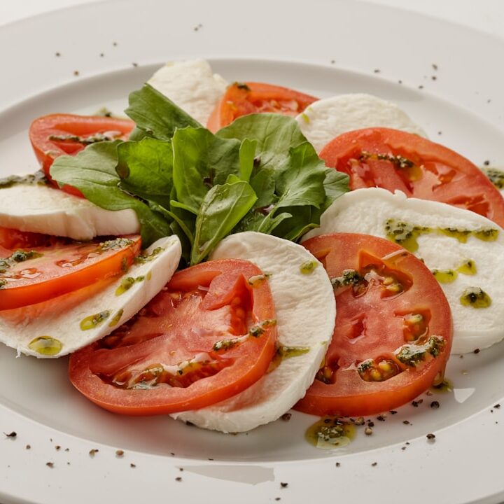 a white plate topped with sliced tomatoes and mozzarella