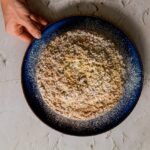 a person holding a plate of food on a table
