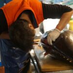 man in orange t-shirt and black pants holding black fish