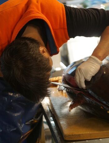 man in orange t-shirt and black pants holding black fish