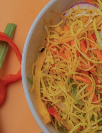 Bowl of noodles with vegetables and red pepper slices