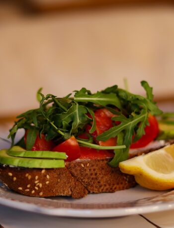 a white plate topped with a sandwich and a slice of lemon