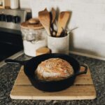a loaf of bread sitting in a skillet on a cutting board