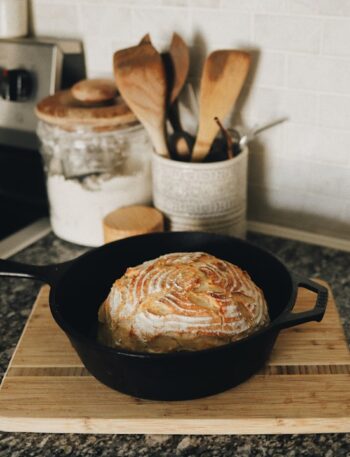 a loaf of bread sitting in a skillet on a cutting board