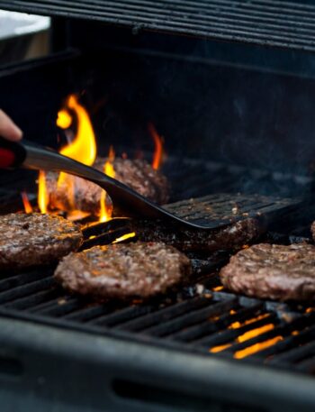 person grilling hamburger patties