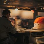 a man sitting at a table with a fake head on top of it