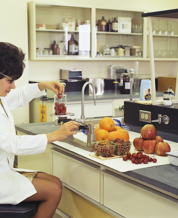 a woman in a white lab coat sitting at a counter in front of a sink