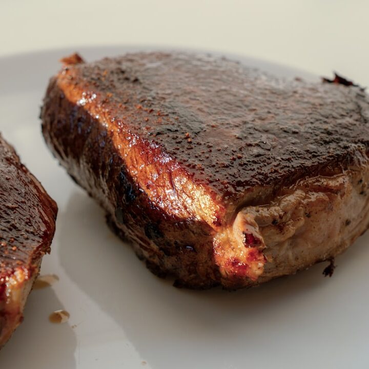 two pieces of steak on a white plate