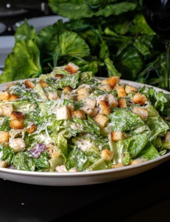 Delicious caesar salad is presented on a table.